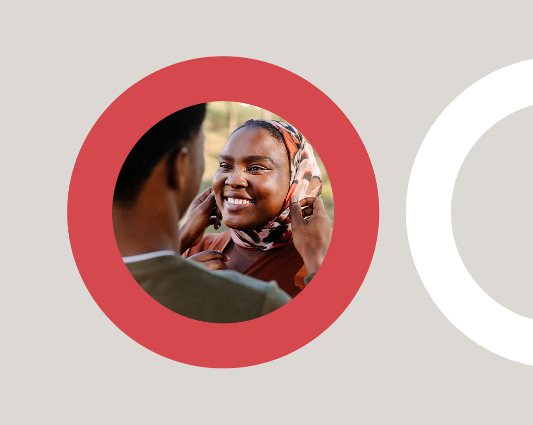 An African woman in traditional dress smiling at someone, in a red circle